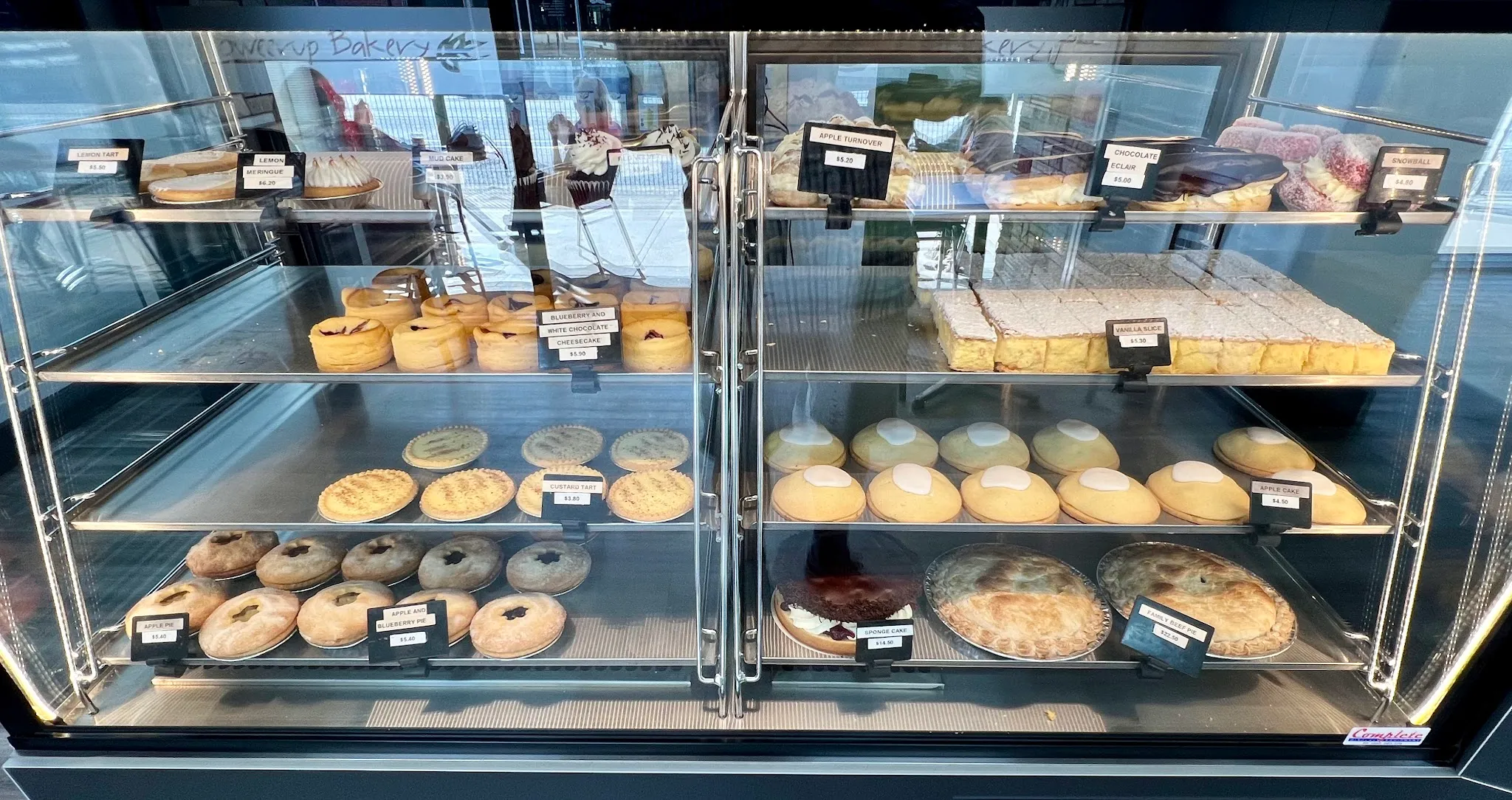 Bakery display cabinet full of pies, tarts, cakes and pastries with price tags