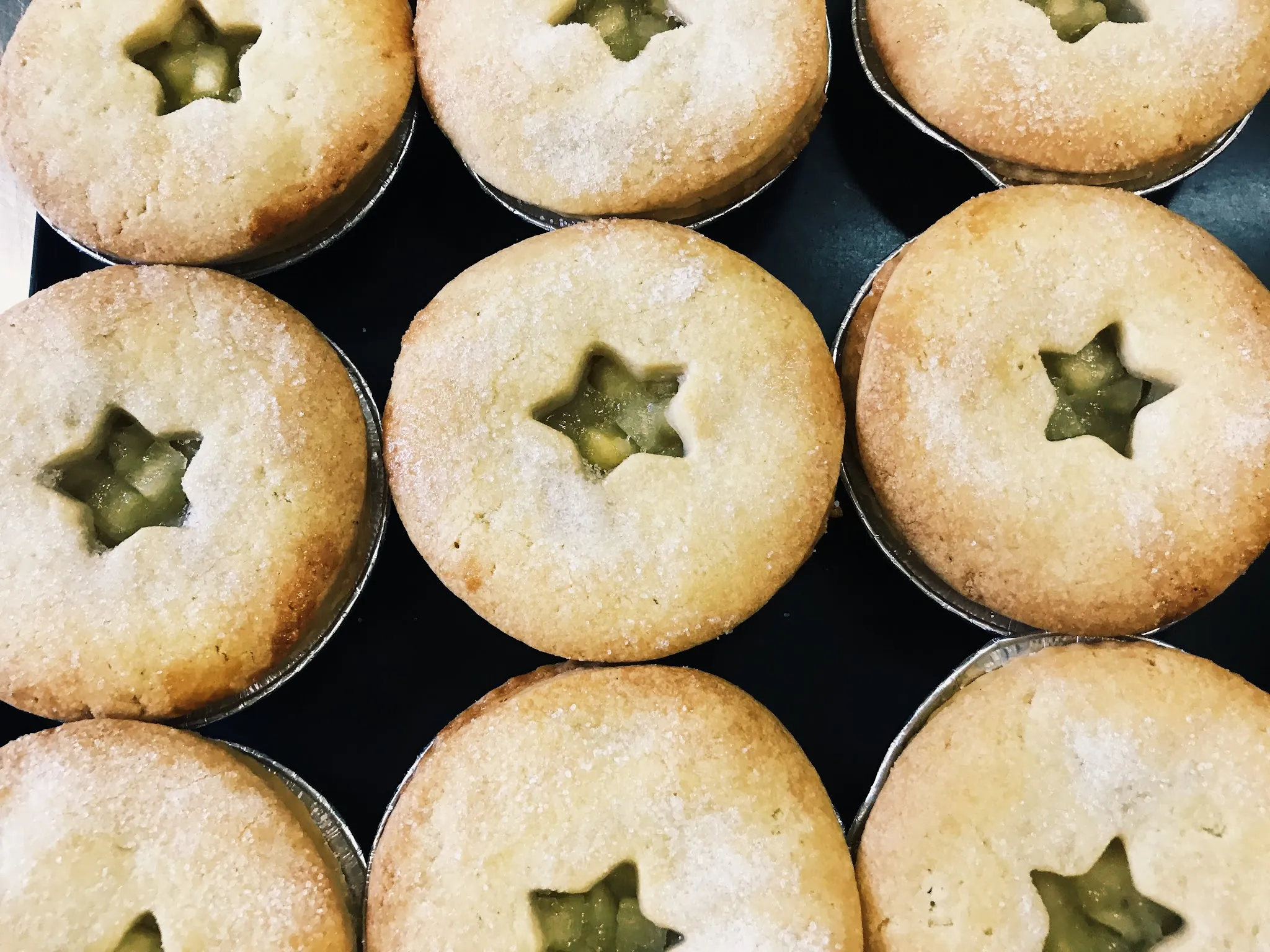Rows of freshly baked mince pies with star shaped pastry cutouts