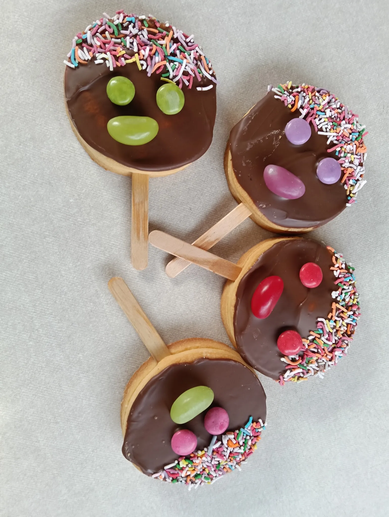 Chocolate biscuit pops decorated as smiley faces with jelly bean features